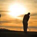 golfer on green backlit sunset